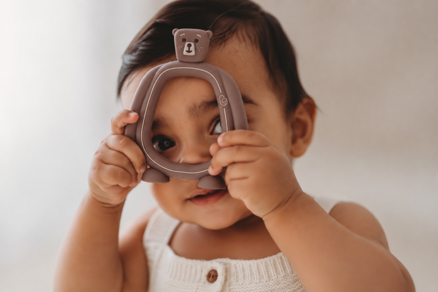 Baby peeking through the handle of the Bear Buddy teether
