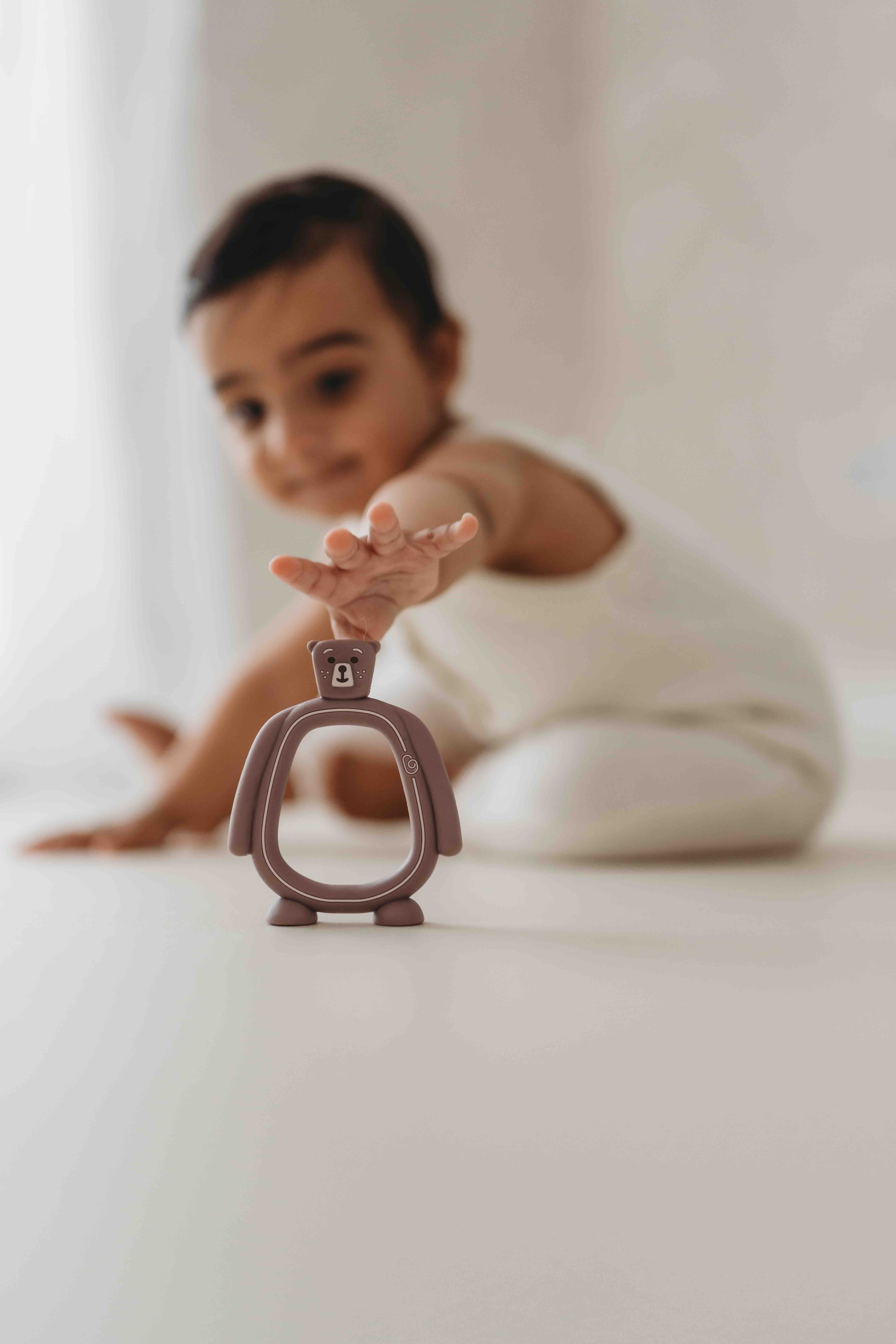 Baby reaching out to touch the Bear Buddy teether