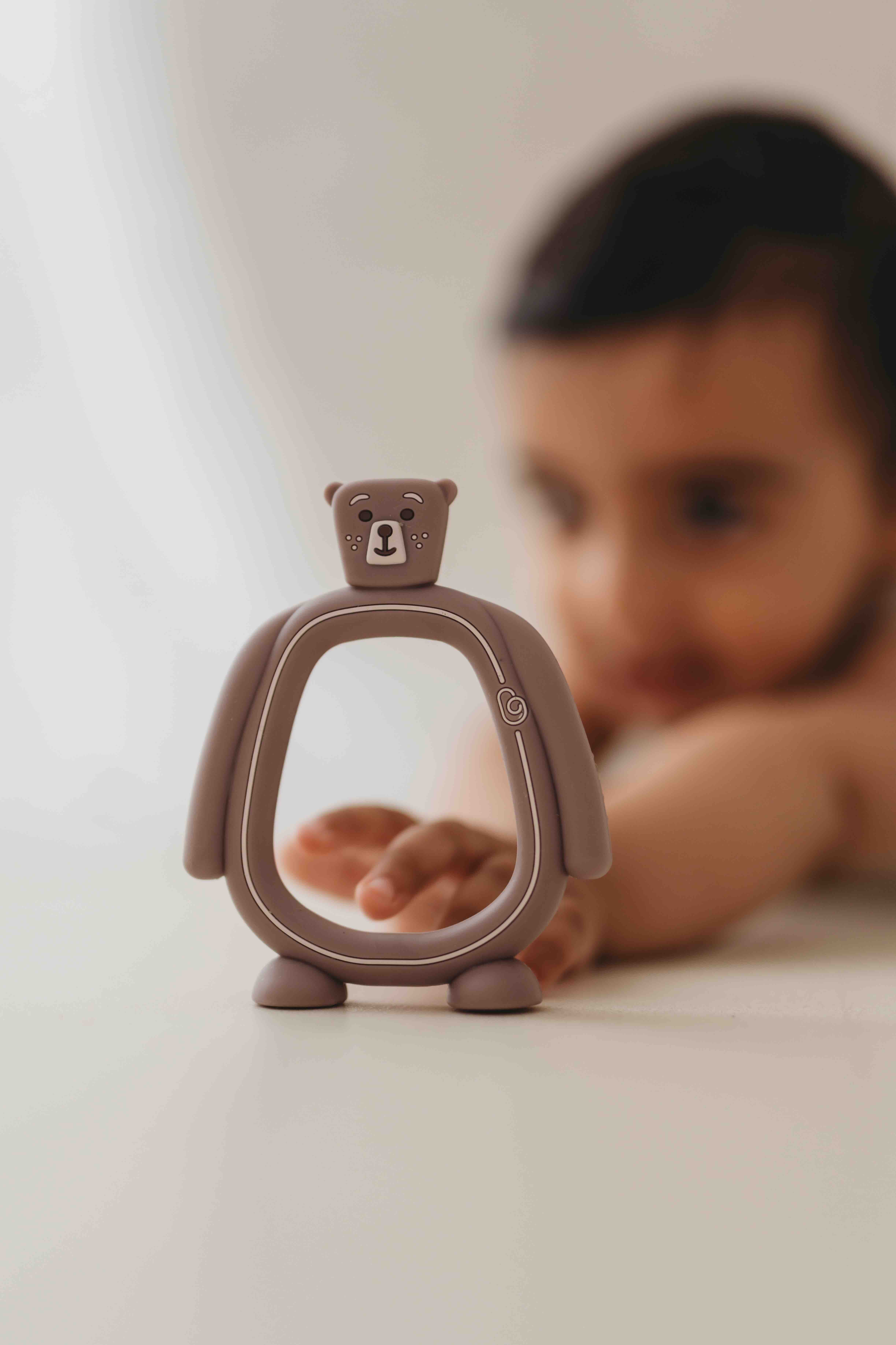 Bear Buddy teether standing beside a baby